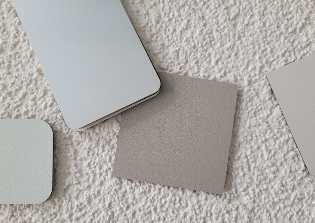 Vier verschiedene Farb- und Materialmuster auf einer grob strukturierten weißen Oberfläche